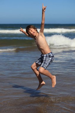 Okyanusun kenarında dans eden neşeli çocuk