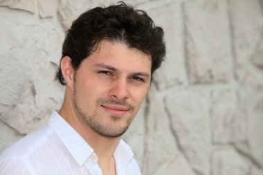 Duvarın yanında duran yakışıklı İspanyol genç adam.