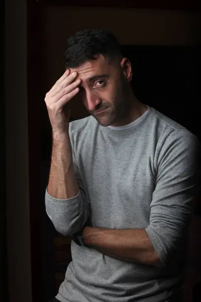 stock image portrait of a puzzled hispanic  man in low lighting on black background