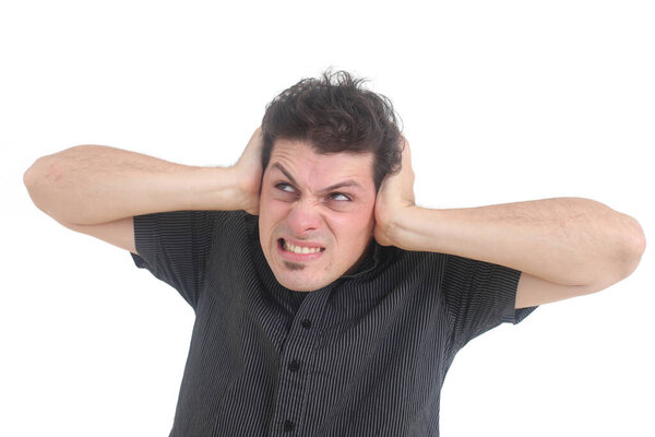 Frustrated and stressed young man  holding head in hands  while standing against white background