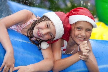 İki neşeli küçük kız gülerek ve oynayarak şişme havuzda su sıçratarak