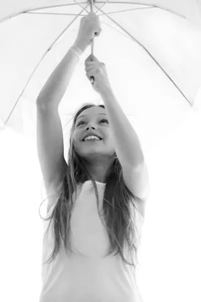 stock image portrait of cheerful preteen girl holding umbrella and looking up smiling in black and white