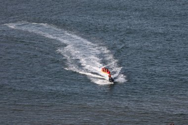  Bir grup insan güneşli bir günde muz teknesine biniyor. Uzaktan yüksek açılı bir açıdan