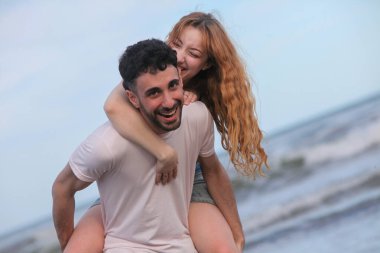 Genç, neşeli ırklar arası çift yaz akşamları okyanus kenarında eğleniyor. 