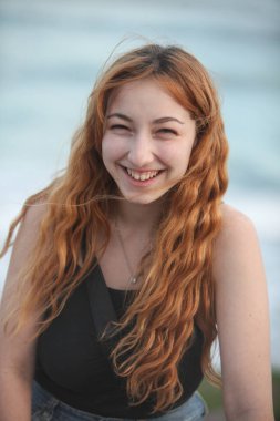 Arka planda okyanusla gülen güzel bir kadının portresi.