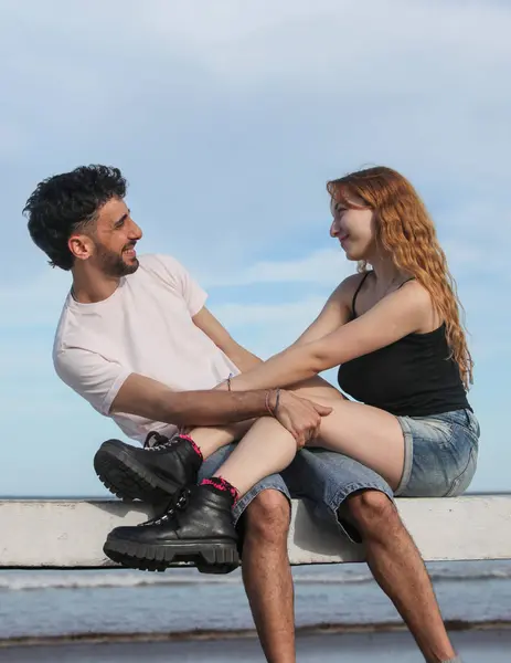 Genç ve sevgi dolu bir çift sahilde oturuyor.