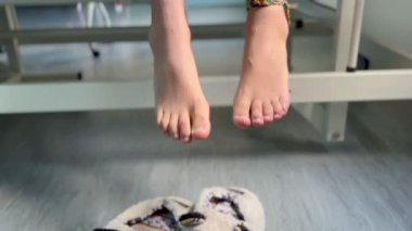 Hastanede genç kızların ayaklarının terlikleriyle yatağın üzerinde otururken.  