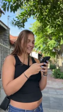 Oldukça neşeli bir genç kız. Yaz günü sokakta cep telefonu kullanıyor. Mesajlaşıyor ve konuşuyor.