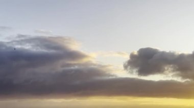 Yaz akşamı gün batımında okyanusta uçan kuşlarla dramatik bir gökyüzü.