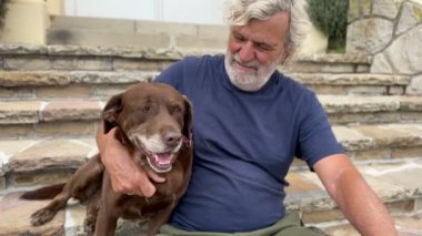 Neşeli son sınıf öğrencisinin portresi. Bahçedeki evinin yanında köpeğiyle oturuyor. 