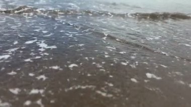 Yaz günü kumsalda yavaş okyanus dalgalarına yakın çekim 