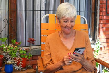 Bahçede akıllı telefon kullanan son sınıf öğrencisi bir kadın.