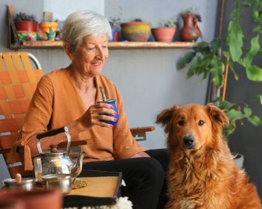 Neşeli, son sınıf öğrencisi, köpeğiyle birlikte terasta içki içen kadın.