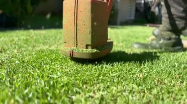 Bahçede çim biçen bir adam var.