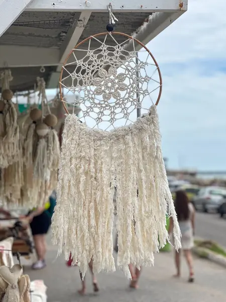 Macrame düş kapanı diğer hediyelik eşyalarla açık hava pazarında takılıyor.