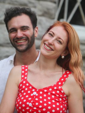 Yaz günü arka planda duvarları olan açık havada aşık genç bir çiftin portresi.