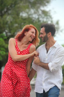 Genç, neşeli melez çift yaz günü parkta yürüyüp konuşuyorlar.