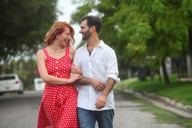 Genç, neşeli melez çift yaz günü parkta yürüyüp konuşuyorlar.