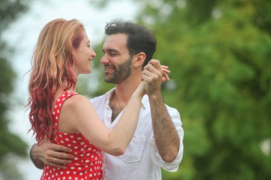 Yaz günü parkta dans eden neşeli genç adam ve kadın.