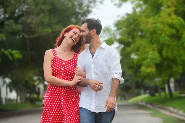 Yazın parkta yürüyen ve konuşan neşeli, melez bir çift.