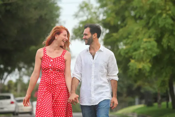 Genç, neşeli melez çift yaz günü parkta yürüyüp konuşuyorlar.