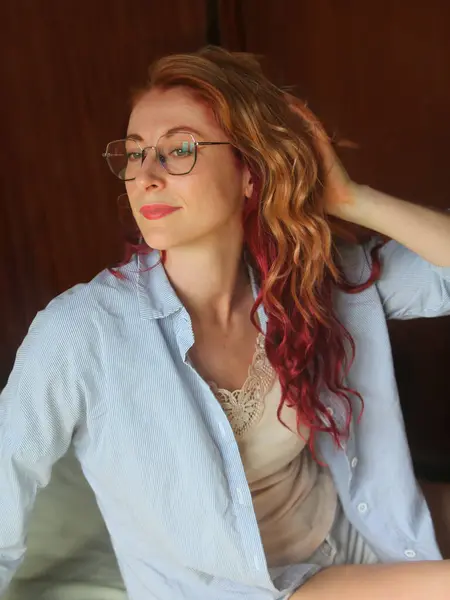 Kızıl saçlı, gözlüklü, güzel bir genç kadının portresi. Yan bakıyor, içeri bakıyor.