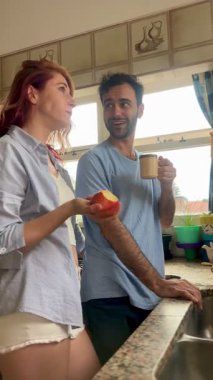 Birbirlerine aşık neşeli bir çift mutfakta birlikte kahvaltı ediyor, gülüyor ve konuşuyor.