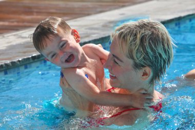 Anne ve küçük oğlu yüzme havuzunda. Çalıyor ve gülüyor