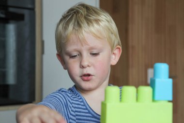 Evden bağımsız oyun ve çocukluk gelişiminde plastik yapı taşlarıyla oynayan küçük çocuk