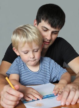 Baba ve küçük çocuk evde birlikte resim çiziyorlar. .