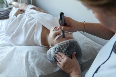 Kadının güzellik kliniğinde ya da kaplıcada profesyonel kozmetik uzmanı tarafından Derma Pen ile tedavi görmesi