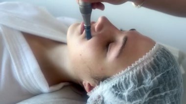 Kadının güzellik kliniğinde ya da kaplıcada profesyonel kozmetik uzmanı tarafından Derma Pen ile tedavi görmesi