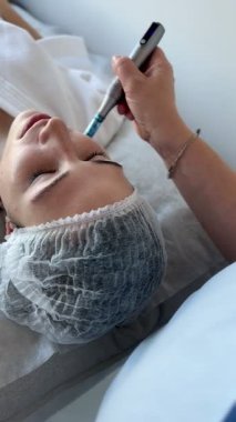 Kadının güzellik kliniğinde ya da kaplıcada profesyonel kozmetik uzmanı tarafından Derma Pen ile tedavi görmesi