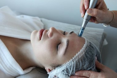 Kadının güzellik kliniğinde ya da kaplıcada profesyonel kozmetik uzmanı tarafından Derma Pen ile tedavi görmesi