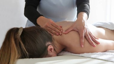  Kadın masaj salonundaki profesyonel bir masözden masaj yaptırıyor masaj masasında losyon şişeleriyle yatıyor.