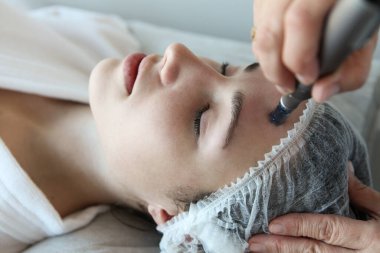 Kadının güzellik kliniğinde ya da kaplıcada profesyonel kozmetik uzmanı tarafından Derma Pen ile tedavi görmesi