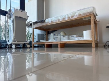  Masaj odasının masası, havluları, ekipmanları ve geniş pencereli güneş ışığıyla..