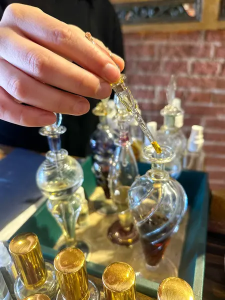  Küçük el yapımı parfüm ve gerekli yağ şişelerinin yakın plan çekiminde bir kadın eli pipet kullanıyor. Doğal, organik ve egzotik koku sunumu.