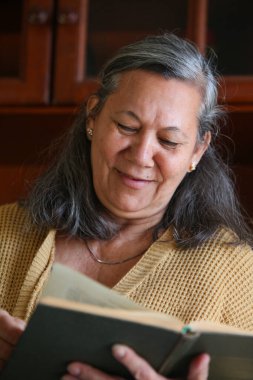 Guaran özellikleri olan yaşlı bir Latin kadının portresi. Elinde sakin ve rahat bir ev ortamında kitap tutuyor. Düşünceli ve rahat görünüyor..