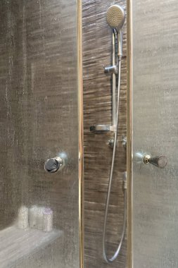  Sert su ve sabun köpüğünden beyaz mineral kalıntısı olan kirli bir duş camı kapısının yakın çekimi. Arka planda bulanık bir duş kabini var. Ortak tuvalet temizleme sorunu.