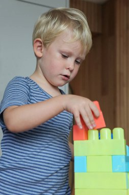 Genç çocuk renkli yapı taşlarıyla içeride oynuyor..