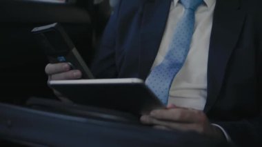 Takside bir adam tablet üzerinde çalışıyor ve telefonda mesajlaşıyor. Yüksek kalite 4k görüntü