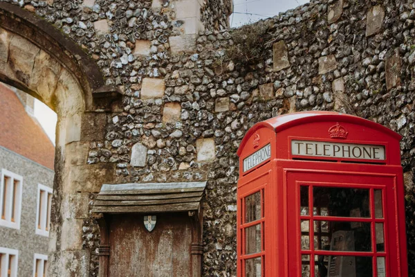 Die Rote Telefonzelle Vor Einer Mittelalterlichen Steinmauer lizenzfreie Stockfotos