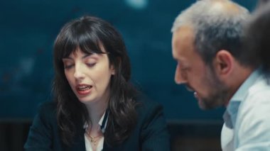 İş kıyafetleri içinde kendinden emin bir kadın yönetici bir şirket toplantısında bir tartışmaya öncülük ediyor. Modern bir ofis ortamında yakın çekim. Liderlik kavramı, takım çalışması ve profesyonel iletişim.