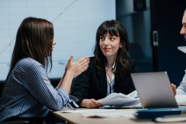 Üst düzey yöneticiler ve asistanlar lüks bir C-suit yönetim kurulunda önemli bir performans değerlendirme toplantısı düzenlerler. Farklı yaşlardan beyaz profesyoneller masa etrafında kağıt ve dizüstü bilgisayarlarla strateji tartışıyor.