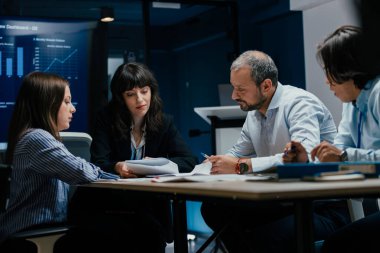 Üst düzey bir şirket yönetim kurulundaki yatırım riskini değerlendiren beyin fırtınası oturumunda aralarında yönetici ve asistanların da yer aldığı dört profesyonel işbirliği yapıyor. Stratejik toplantı, lüks ofis ortamında takım çalışması ve analizleri gösteriyor..