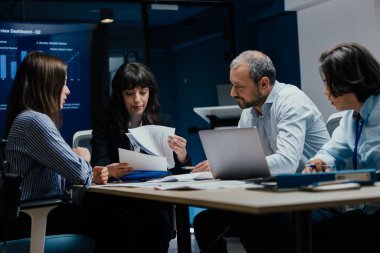 Üst düzey bir şirket yönetim kurulundaki yatırım riskini değerlendiren beyin fırtınası oturumunda aralarında yönetici ve asistanların da yer aldığı dört profesyonel işbirliği yapıyor. Stratejik toplantı, lüks ofis ortamında takım çalışması ve analizleri gösteriyor..