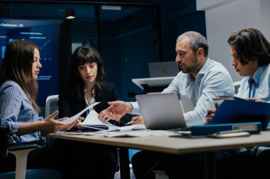 Üst düzey bir şirket yönetim kurulundaki yatırım riskini değerlendiren beyin fırtınası oturumunda aralarında yönetici ve asistanların da yer aldığı dört profesyonel işbirliği yapıyor. Stratejik toplantı, lüks ofis ortamında takım çalışması ve analizleri gösteriyor..