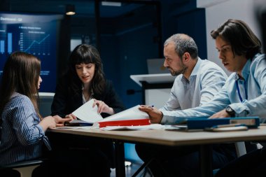 Üst düzey bir şirket yönetim kurulundaki yatırım riskini değerlendiren beyin fırtınası oturumunda aralarında yönetici ve asistanların da yer aldığı dört profesyonel işbirliği yapıyor. Stratejik toplantı, lüks ofis ortamında takım çalışması ve analizleri gösteriyor..