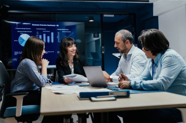 Üst düzey bir şirket yönetim kurulundaki yatırım riskini değerlendiren beyin fırtınası oturumunda aralarında yönetici ve asistanların da yer aldığı dört profesyonel işbirliği yapıyor. Stratejik toplantı, lüks ofis ortamında takım çalışması ve analizleri gösteriyor..